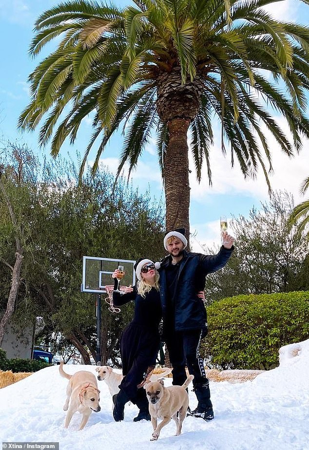 White Christmas: She and Rutler lifted some champagne glasses, as they snapped a photo on the fresh grass, swinging in identical black Santa hats